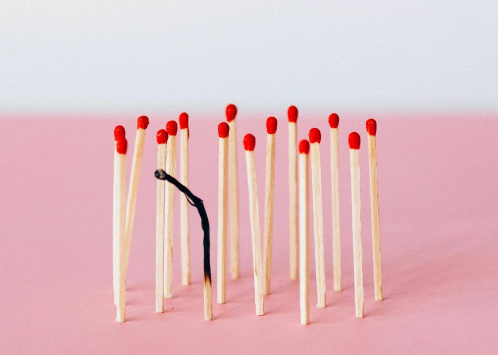 Group of unlit matches with one burnt matchstick in the centre, symbolizing burnout or exhaustion.