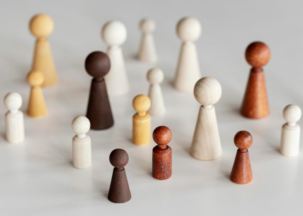 Group of wooden figurines of varying sizes and colours, symbolizing diversity and community.